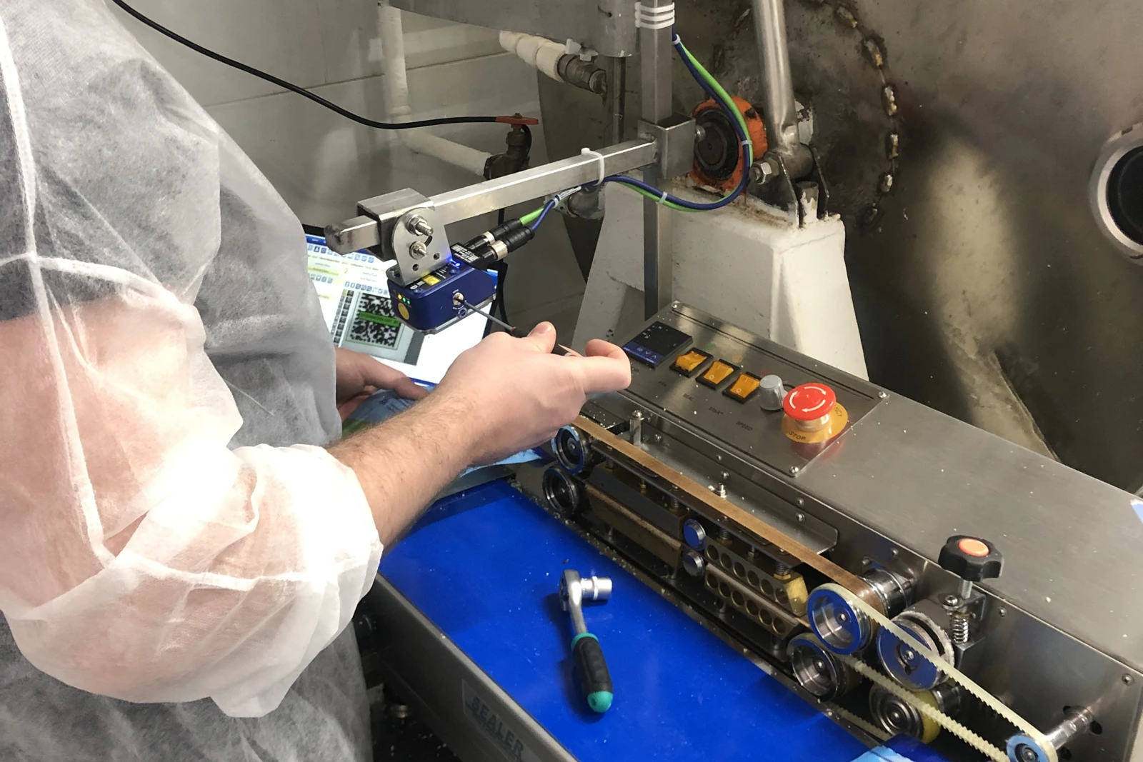 A technician tuning the inline code scanner on a running sealer