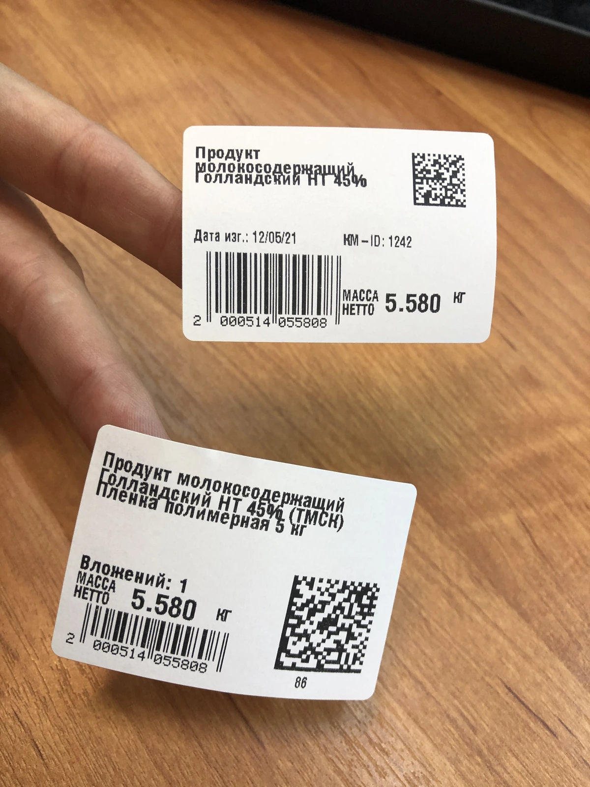 Two printed labels held up, each with a unique DataMatrix and barcode